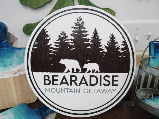 A round sign for Bear's Paradise Mountain Getaway, featuring custom cabin pine trees wilderness bears textured PVC, weather fade resistant, waterproof UV printed color logo business commercial signage